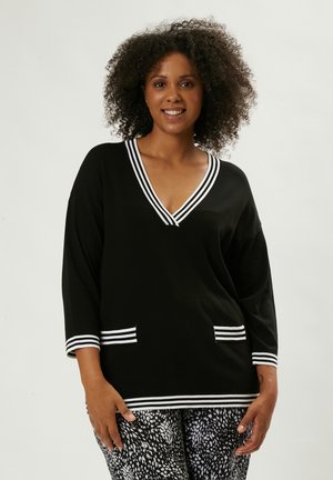Maglione nero a V con accenti a strisce bianche sul collo e sui polsini; presenta due tasche frontali. Tessuto morbido, vestibilità comoda.