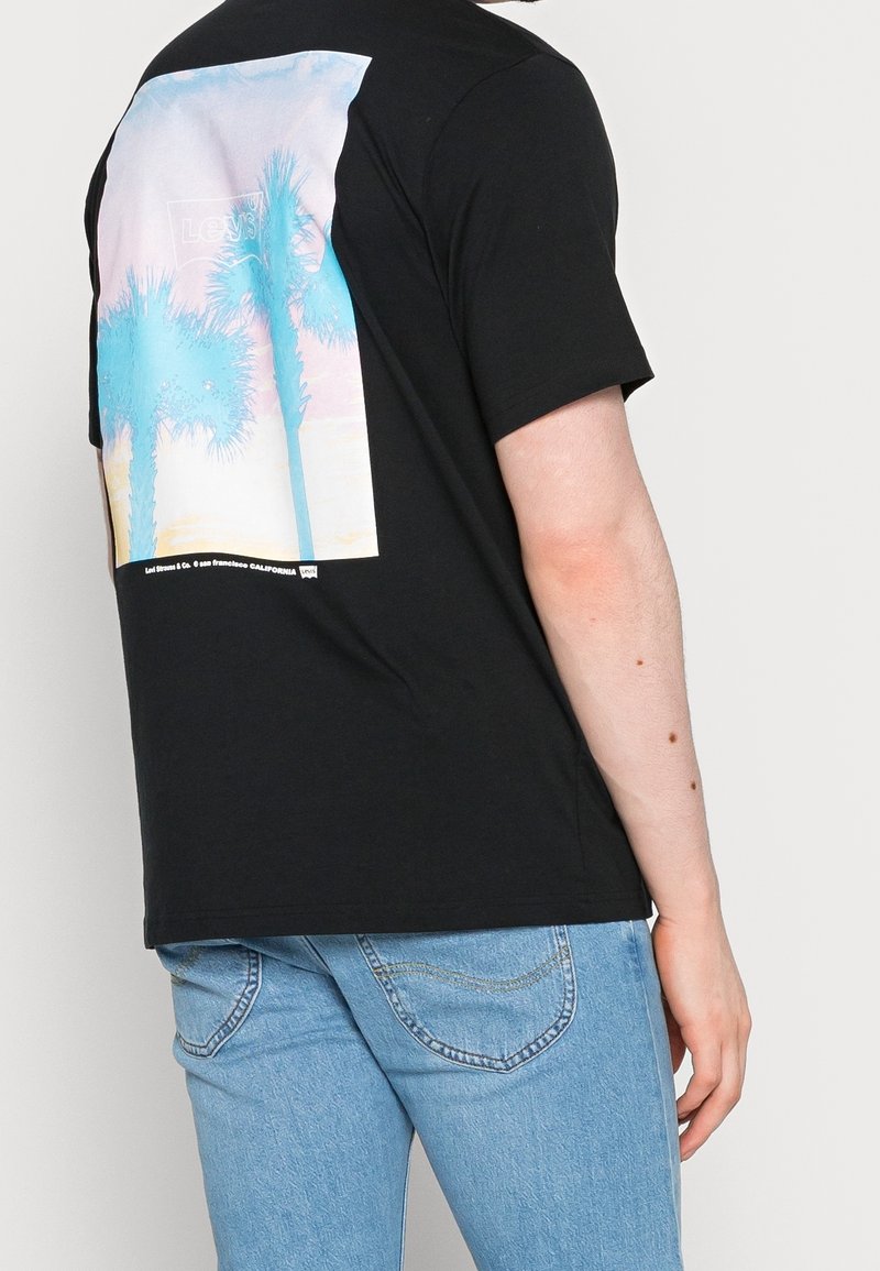 Černé bavlněné tričko s barevným grafickým motivem palmy na zadní straně, s pohodlným střihem a krátkými rukávy.