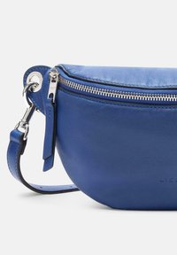 Blaue Lederhandtasche mit runder Form, silbernen Reißverschlussbeschlägen und abnehmbarem Tragegurt. Glatte Textur und minimalistisches Design.