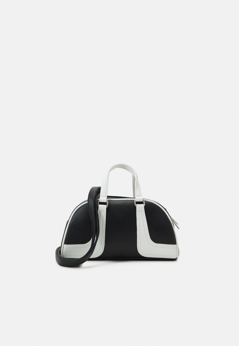 Petit sac à main noir et blanc de forme courbe, deux poignées blanches sur le dessus et une bandoulière noire amovible.