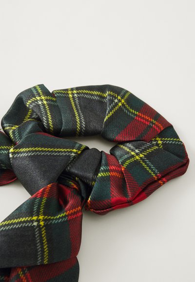 Tartan šalikas su žaliais, raudonais ir geltonais raštais, pagamintas iš lygios medžiagos su mazgo dizainu, demonstruojantis blizgų paviršių ir tekstūrą.