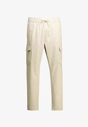 Bēšas ikdienas kravas bikses ar elastīgu jostu, auklu un uzkritušām kabatām abās kāju pusēs, attēlotas uz baltā fona.