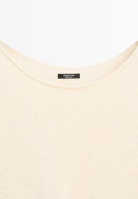 Pull en maille couleur crème avec un col rond et une étiquette noire indiquant « Massimo Dutti Made in China » à l'encolure.