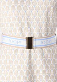 Ceinture blanche avec des accents rayés bleu clair et beige, dotée d'une boucle en métal. Elle présente un motif floral sur le tissu.