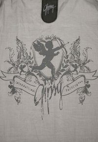 Gray silhouette of a winged cherub holding a bow and arrow surrounded by decorative floral elements and banners with text on white fabric.