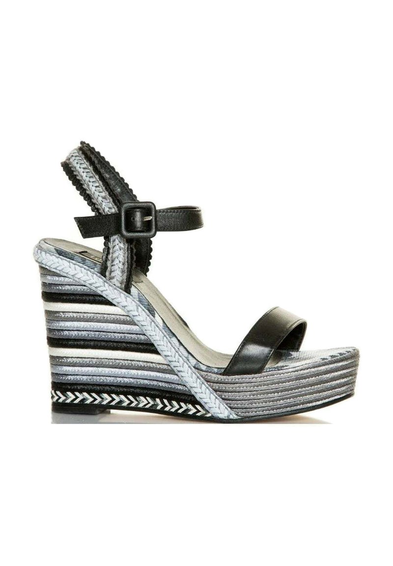 Sandalia cuña negra con una amplia tira en la puntera y tira ajustable en el tobillo. La cuña a rayas presenta texturas y patrones en gris, negro y blanco.