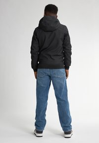 Schwarze Kapuzenjacke, blaue Jeans, sichtbare Nähte und eine lockere Passform. Einfaches Design mit einer glatten Textur und lässigem Stil.