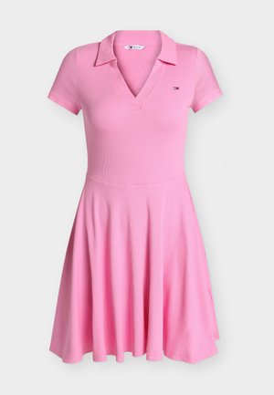 Robe polo rose à manches courtes avec une jupe évasée et un petit logo sur la poitrine, présentée sur un fond uni.