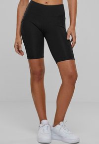 Pantalones cortos de ciclismo negros de cintura alta, hechos de un material elástico, con una textura suave, forma ajustada y sin patrones visibles.