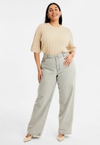 Beige ribbat tröja med korta ärmar, ihop med högmidjade ljusgrå vida jeans och spetsiga beige ballerinan.
