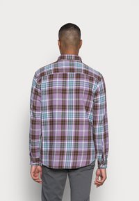 Koszula w kratę w kolorze fioletowym, brązowym i niebieskim. Długie rękawy z mankietami na guziki, klasyczny kołnierzyk i zaokrąglony dół. Miękka tekstura, uporządkowany wzór.