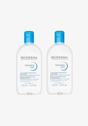 Bioderma Hydrabio H2O, zwei durchsichtige 500-ml-Flaschen mit blauen Verschlüssen. Die Etiketten haben einen weißen Hintergrund und blaue Schrift, die die Anwendungsbereiche des Produkts beschreibt.