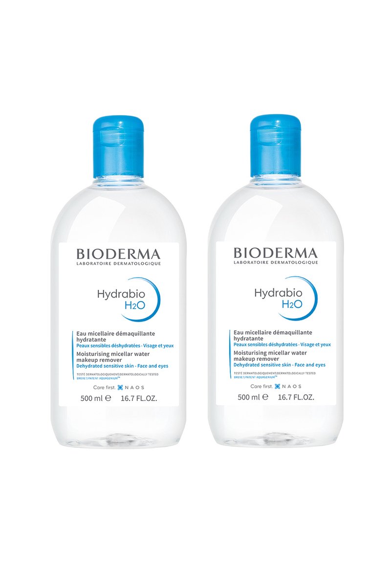Bioderma Hydrabio H2O, due bottiglie trasparenti da 500 ml con tappi blu. Le etichette mostrano uno sfondo bianco e testi blu che descrivono gli utilizzi del prodotto.