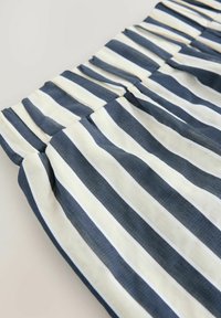 Primo piano di tessuto a righe con linee orizzontali blu navy e crema, con una texture stropicciata, che mostra dettagli arricciati nella parte superiore.