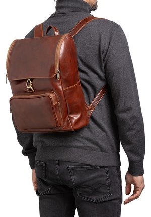 Zaino in pelle marrone con zip superiore, tasca frontale e spallacci regolabili. Presenta accessori in ottone e una texture liscia.