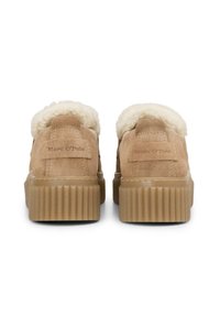 Beige Wildlederschuhe mit einem flauschigen weißen Innenfutter, runder Spitze und geriffelter Gummisohle. Mit eingestanztem "Marc O'Polo"-Logo an der Ferse.
