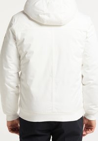 Witte donzenjas met capuchon, met een gladde textuur, elastische manchetten en een geribde zoom. Het ontwerp aan de achterkant bevat zichtbare stiksel details.