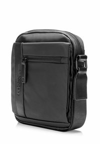 Czarna nylonowa torba na ramię o prostokątnym kształcie, z przednią kieszenią na zamek błyskawiczny i regulowanym paskiem. Gładka faktura i subtelne logo.