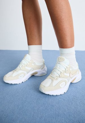 Baskets beiges et blanches avec des matériaux en mesh et en daim, dotées d'une surface texturée, d'un bout rond et d'un système de laçage.