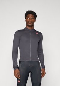 Maillot de cyclisme à manches longues pour homme en gris foncé, avec une fermeture éclair à l'avant, un tissu texturé et un petit logo sur la poitrine.