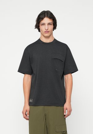 T-shirt nero a maniche corte con vestibilità rilassata, dotato di taschino sul petto e un logo discreto. Tessuto testurizzato con una finitura liscia e morbida.