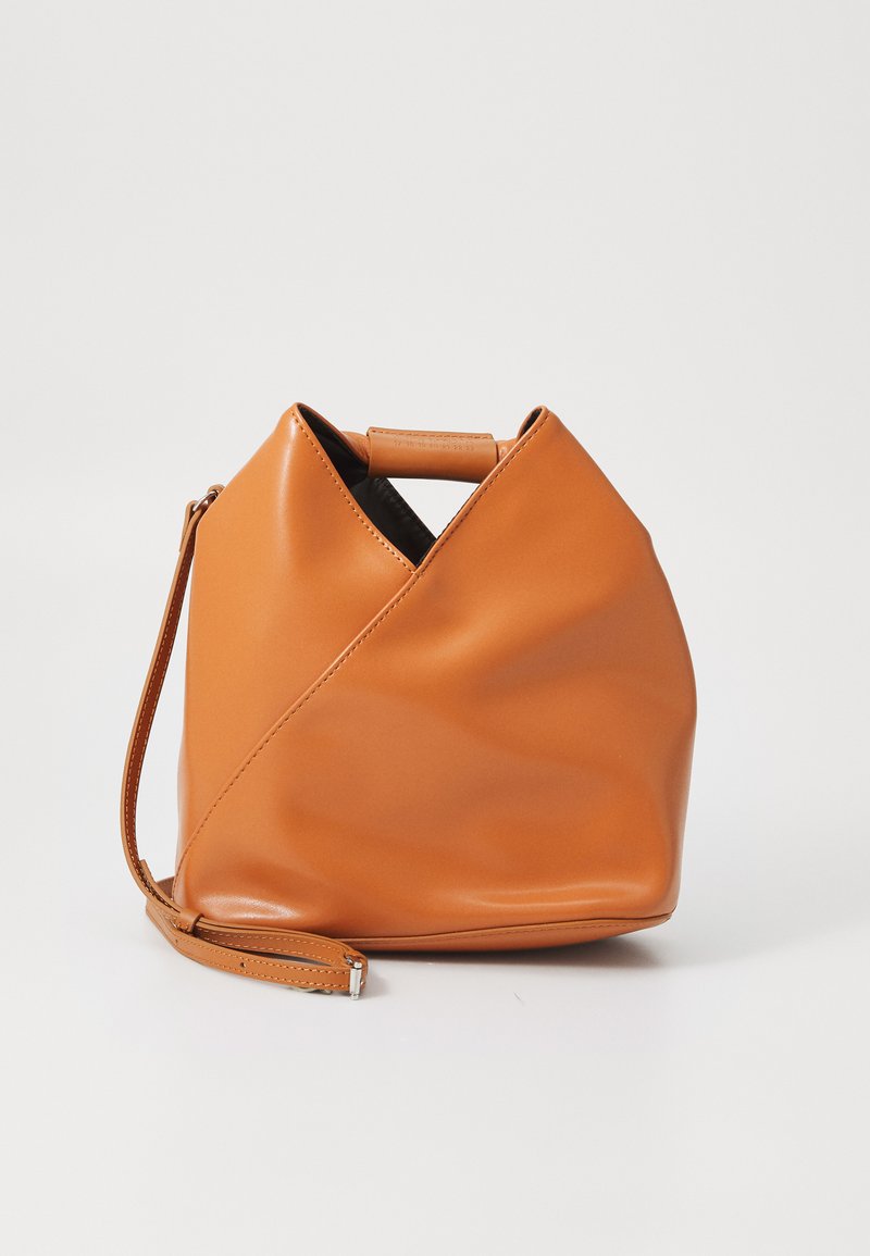 Bolsa de couro castanho-claro com um design único de dobras triangulares, alça superior e alça de ombro destacável, em fundo branco.