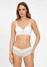 Ensemble en dentelle blanche comprenant un soutien-gorge et une culotte assortis, avec un design de bonnets lisses et moulés, des bretelles ajustables et des accents de boutons décoratifs.
