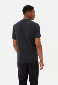 Donkergrijze T-shirt met korte mouwen en een ronde hals, gemaakt van zacht materiaal. Achteraanzicht toont een gladde textuur en details van de schoudernaad.