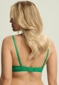 Zielony biustonosz z regulowanymi ramiączkami i zapięciem na haftkę. Wykonany z gładkiego materiału z półprzezroczystym tyłem i minimalistycznym designem.