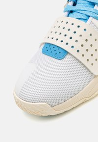Witte mesh sportshoe met een blauwe accent. Voorzien van een geperforeerde band, verstevigde neus en een gestructureerde rubberen zool voor grip.