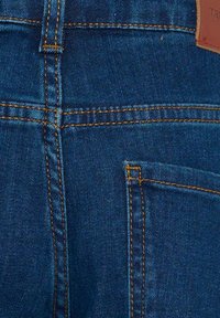 Jeans in denim blu scuro con cuciture contrastanti arancioni. Presentano tasche posteriori e una texture liscia, che enfatizzano la durata e la vestibilità.