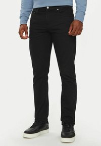 Jeans in denim neri con vestibilità slim, caratterizzati da un classico design a cinque tasche e hardware argentato. Abbinati a sneakers nere.