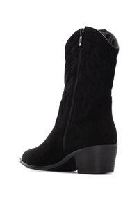 Botas de vaquero de ante negro con cremallera lateral, tacón curvado y detalles texturizados en el eje. Acabado suave con puntera ligeramente afilada.