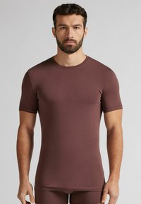 Kawowy, krótki rękaw, dopasowana koszula wykonana z miękkiego, elastycznego materiału. Posiada okrągły dekolt i gładką teksturę.