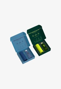 Deux boîtes de produits : une boîte bleue contenant un gel douche et un cylindre bleu foncé, et une boîte verte contenant un spray pour le visage et un cylindre jaune vif.