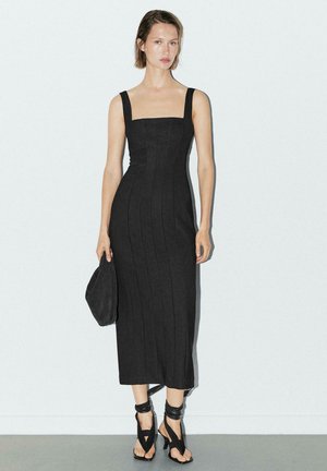 Černé midi šaty s vypasovaným střihem a čtvercovým výstřihem, se širokými ramínky a vertikálními švy. Osvěženo černými sandály na vysokém podpatku a psaníčkem.