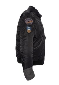 Giacca bomber nera in nylon lucido con colletto e polsini a coste. Presenta toppe ricamate sul braccio sinistro e tasche con zip.