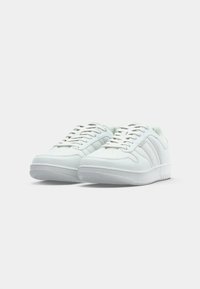 White sneakers with a smooth leather upper, textured rubber sole, and three stitched stripes on each side. Laces and perforations for breathability.