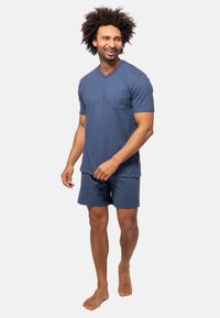 Mørkeblå V-hals t-shirt med brystlomme, korte ærmer, parret med matchende shorts. Stoffet ser blødt, let og afslappet ud.