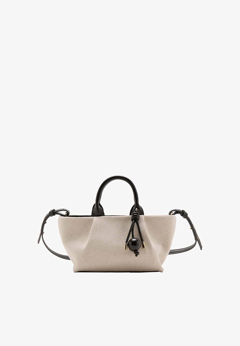 Sac à main en toile beige avec des anses en cuir noir et une bandoulière réglable, avec un détail décoratif de perle noire et de nœud.