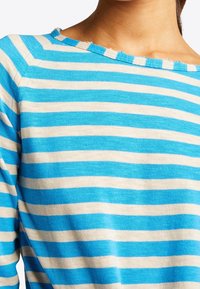 Sweter w paski, lekki materiał, posiada poziome pasy w kolorze niebieskim i kremowym, dekolt w serek z surowym wykończeniem, miękka tekstura.