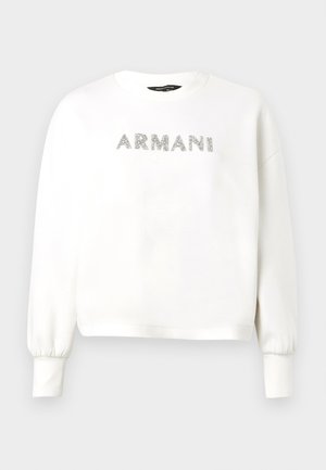 Bluza albă cu manșete rib și un decolteu rotund. „ARMANI” scris cu sclipici argintiu pe piept. Material moale, design scurtat.