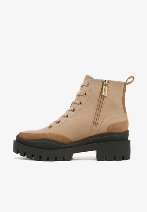 Beige canvas ankle boots with suede accents, gold-tone hardware, front lacing, side zipper, and sturdy black rubber sole with tread.