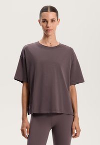 Grå löst sittande t-shirt med korta ärmar, rund halsringning och sidoflikar. Tillverkad av mjukt tyg med en slät struktur och minimala sömdetaljer.