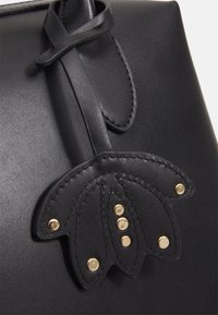 Musta nahkainen käsilaukku, jossa tasainen pinta, kukkakoristeinen nahkaosio ja kultaiset niittiyksityiskohdat. Suljetaan tyylikkäällä nahkahihnalla.