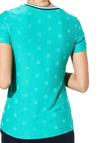 Camiseta de manga corta en color turquesa con un sutil patrón de hojas por toda la prenda, escote redondo con un ribete en contraste y un diseño ajustado.