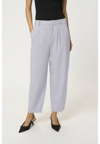 Jasnoszare dopasowane spodnie o gładkiej teksturze, z plisowanym przodem i bocznymi kieszeniami, zestawione z czarnymi szpilkami o spiczastym nosku.