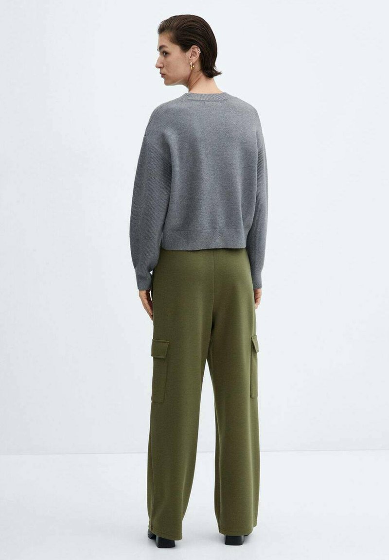 Suéter corto gris de material de punto, combinado con pantalones cargo verdes de pierna ancha que cuentan con dos bolsillos laterales. Diseño sencillo, textura suave.