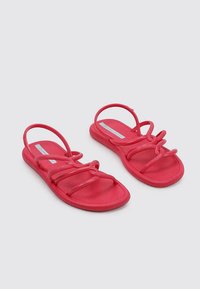 Sandalias rojas de goma con múltiples tiras delgadas y una suela texturada. La suela es plana y flexible, apta para un uso casual.