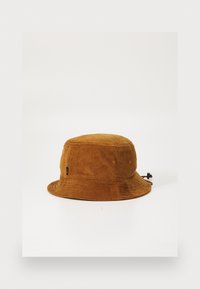 Brun kordfløjl bucket hat med en rund krone og bred skygge, der har små lufthuller og et justerbart snoretræk på siden.